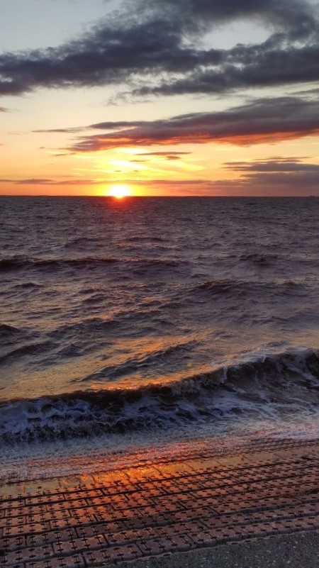 Sunset from Heacham Beach with the waves lapping over the edge of the dam.